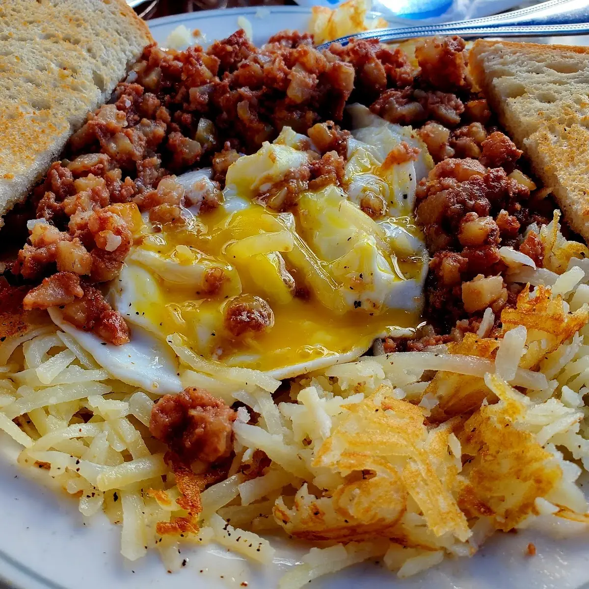 Hash Brawns Under Corned Beef Hash Topped with over Easy Eggs and Italian Buttered Toast