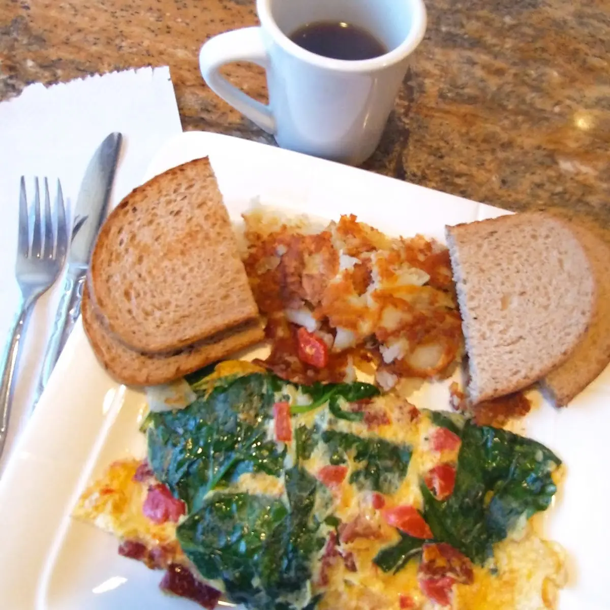 Omelette with Spinach and Sun-Dried Tomatoes Served with Breakfast Potatoes and Toast