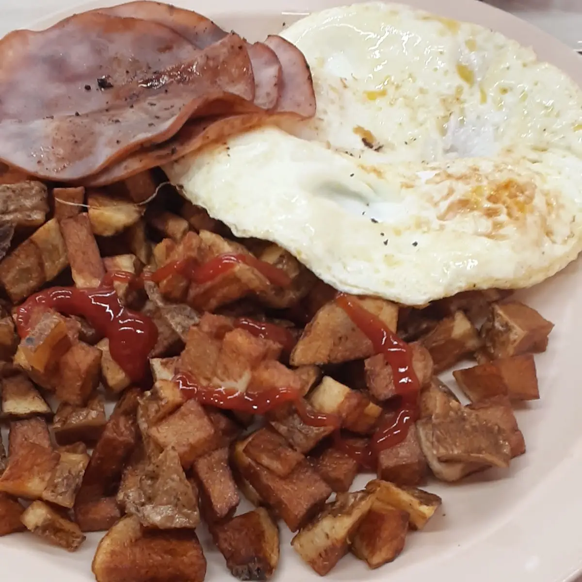 Two Eggs Cooked over Medium with Home Fries Raisin Toast and Ham