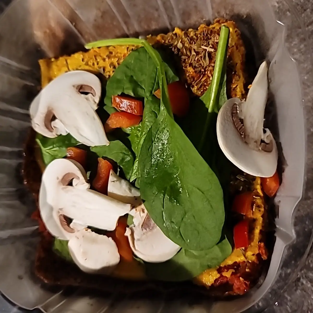 Raw Pizza Slice with Tomatoes Mushrooms and Spinach