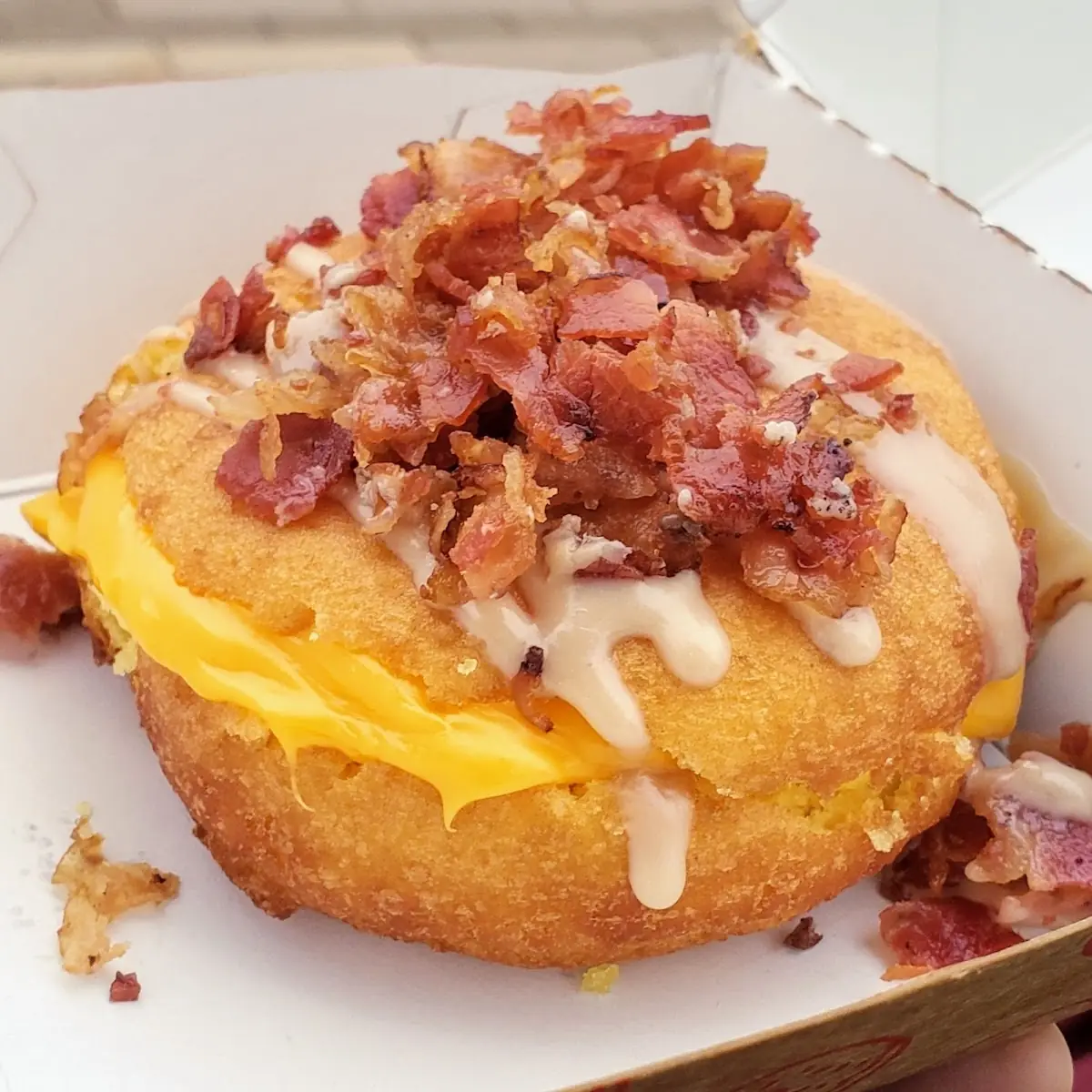 Egg and Cheese on a Donut with Maple Drizzle and Bacon Bits