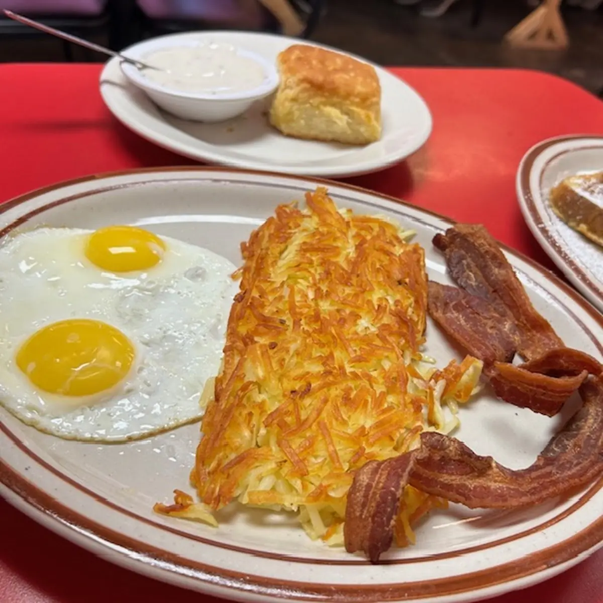 Two Sunny Side Crispy Hash Browns Bacon and a Biscuit with Gravy