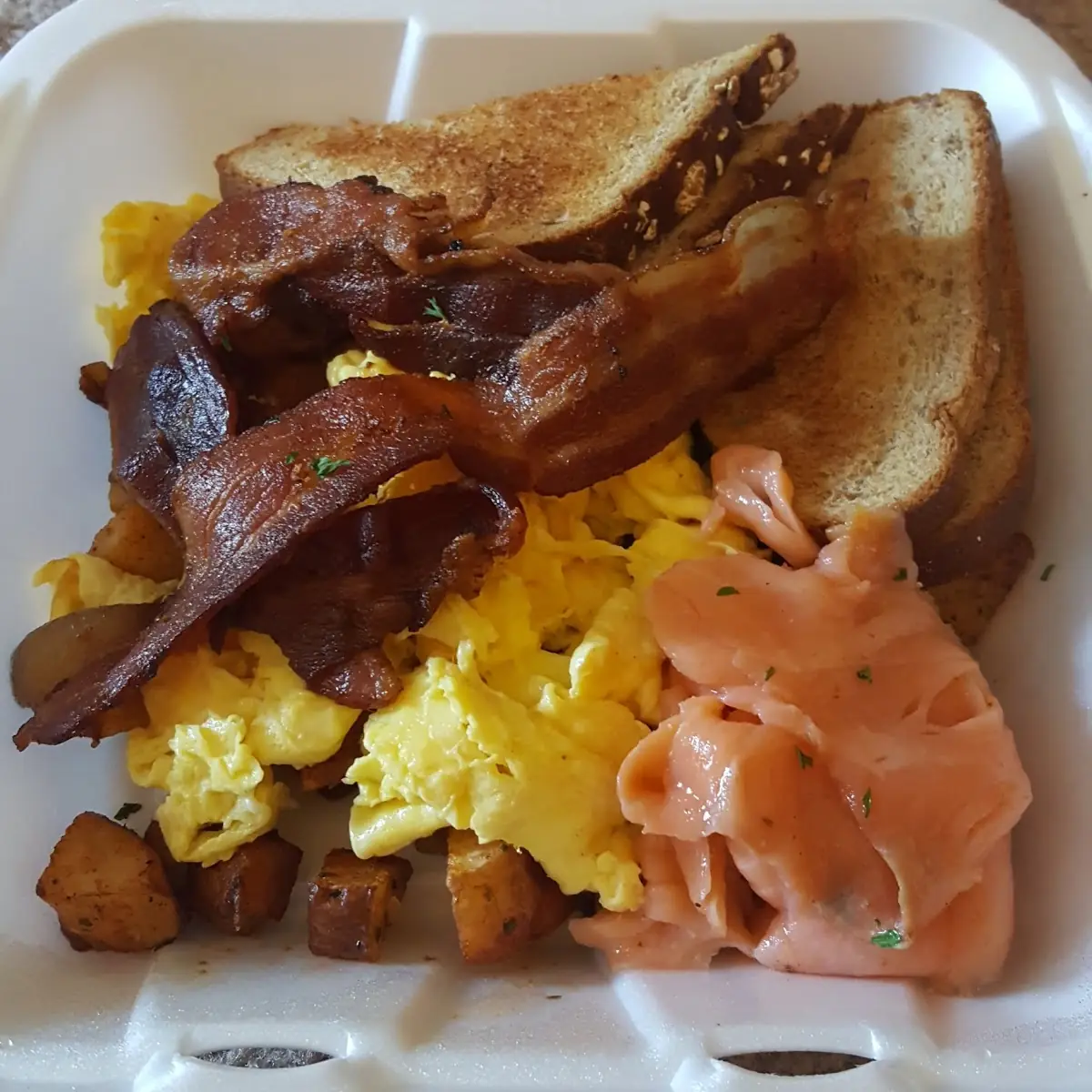 Three Eggs Scrambled Soft with Lox and Bacon Buttered Wheat Toast and Homefries