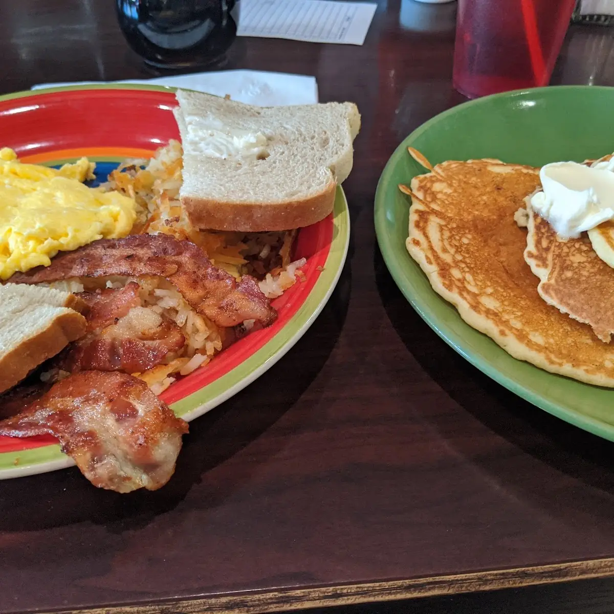 Two Eggs Scrambled with Bacon Hash Browns and Rye Toast with a Stack of Pancakes