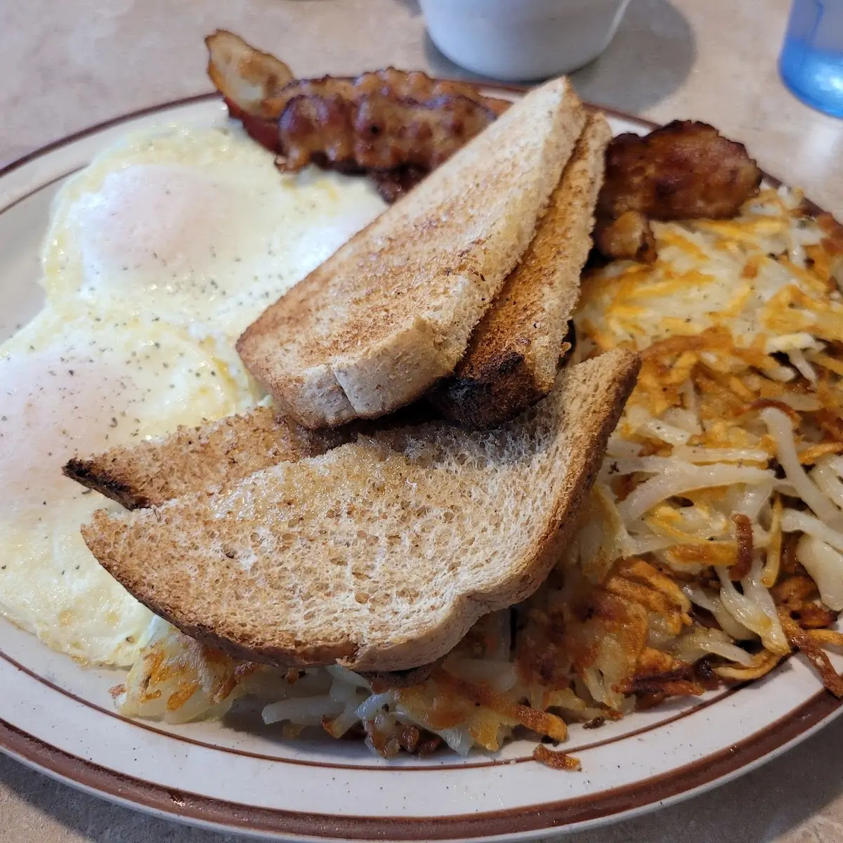 Three Overeasy Eggs Crispy Hash Browns Bacon and Wheat Toast