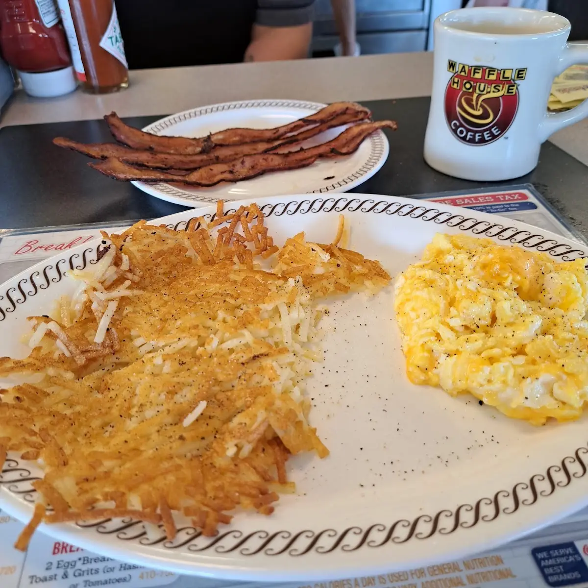 Two Eggs Scrambled with Cheese Hashbrown Scattered Side of Bacon Cooked Well