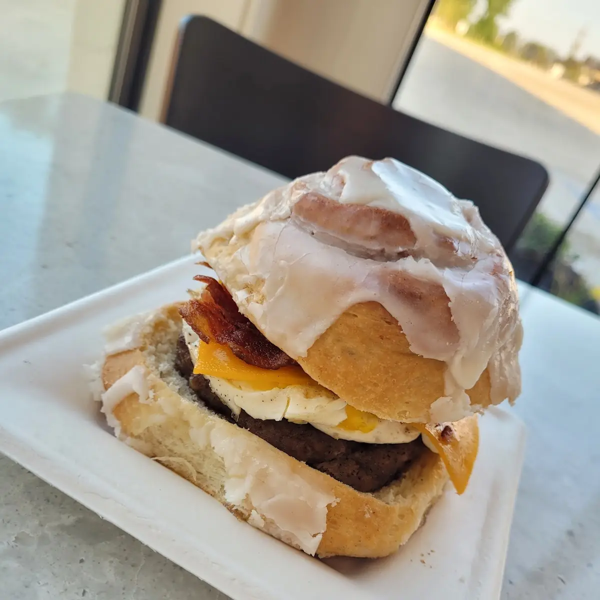 Ultimate Breakfast Sandwich Cinnamon Roll Cut in Half Filled with Sausage Egg Bacon and Cheese