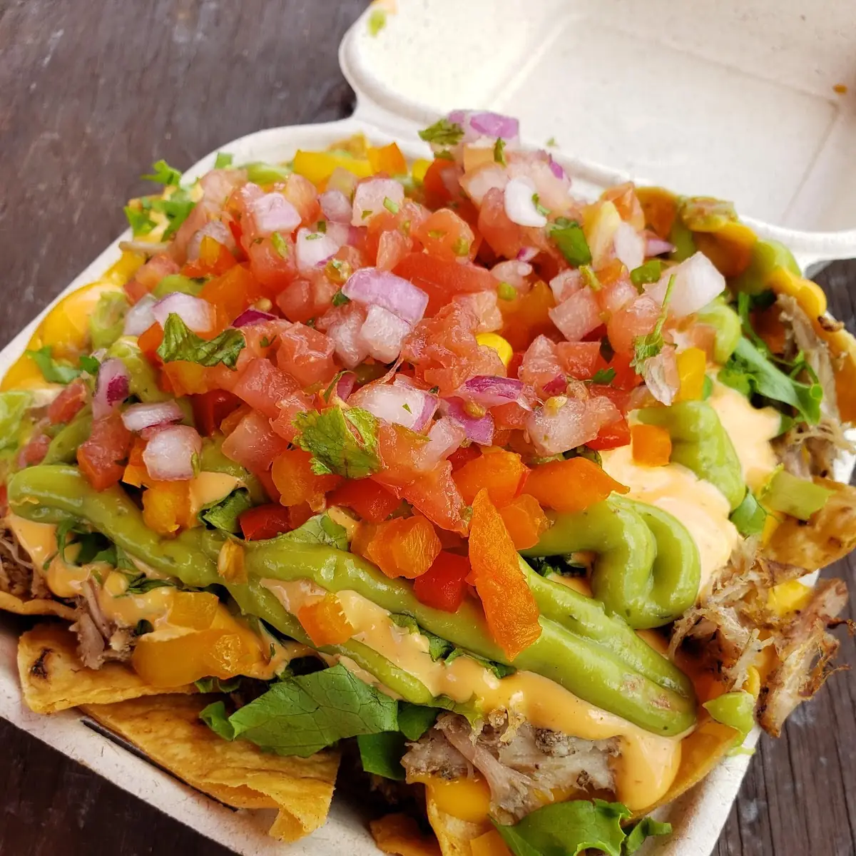 Nachos Carnitas Pork with Lettuce Corn Shredded Cheese Guacamole Sour Cream and Bacon