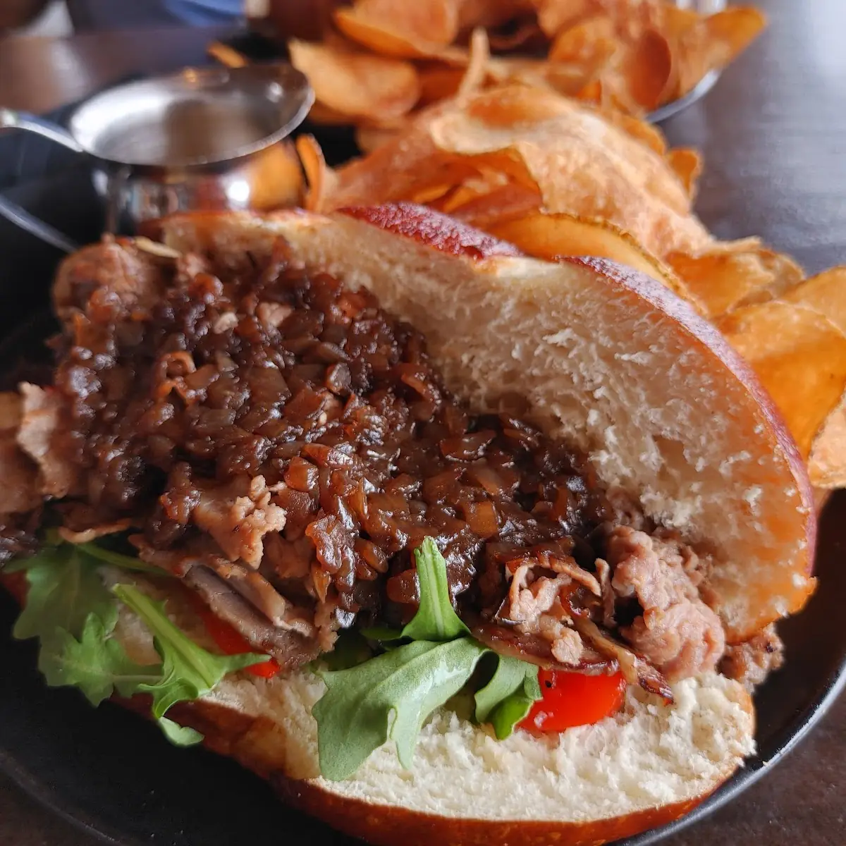 Rib-Eye Steak Sandwich with Caramelized Onions Provolone Garlic Aïoli Au Jus on Sourdough Roll
