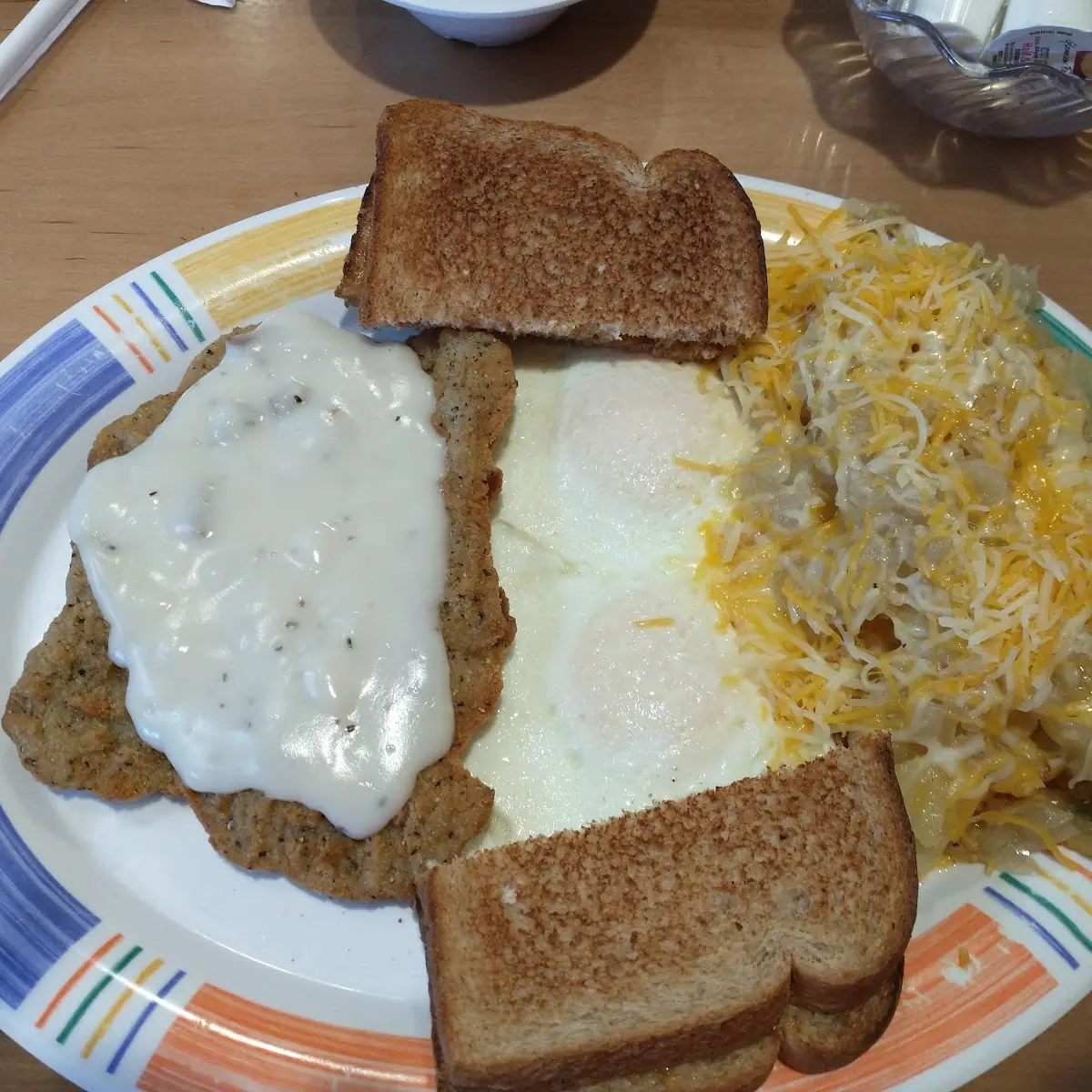 Country Fried Steak with over Medium Eggs and Home Fries with Cheese and Onions