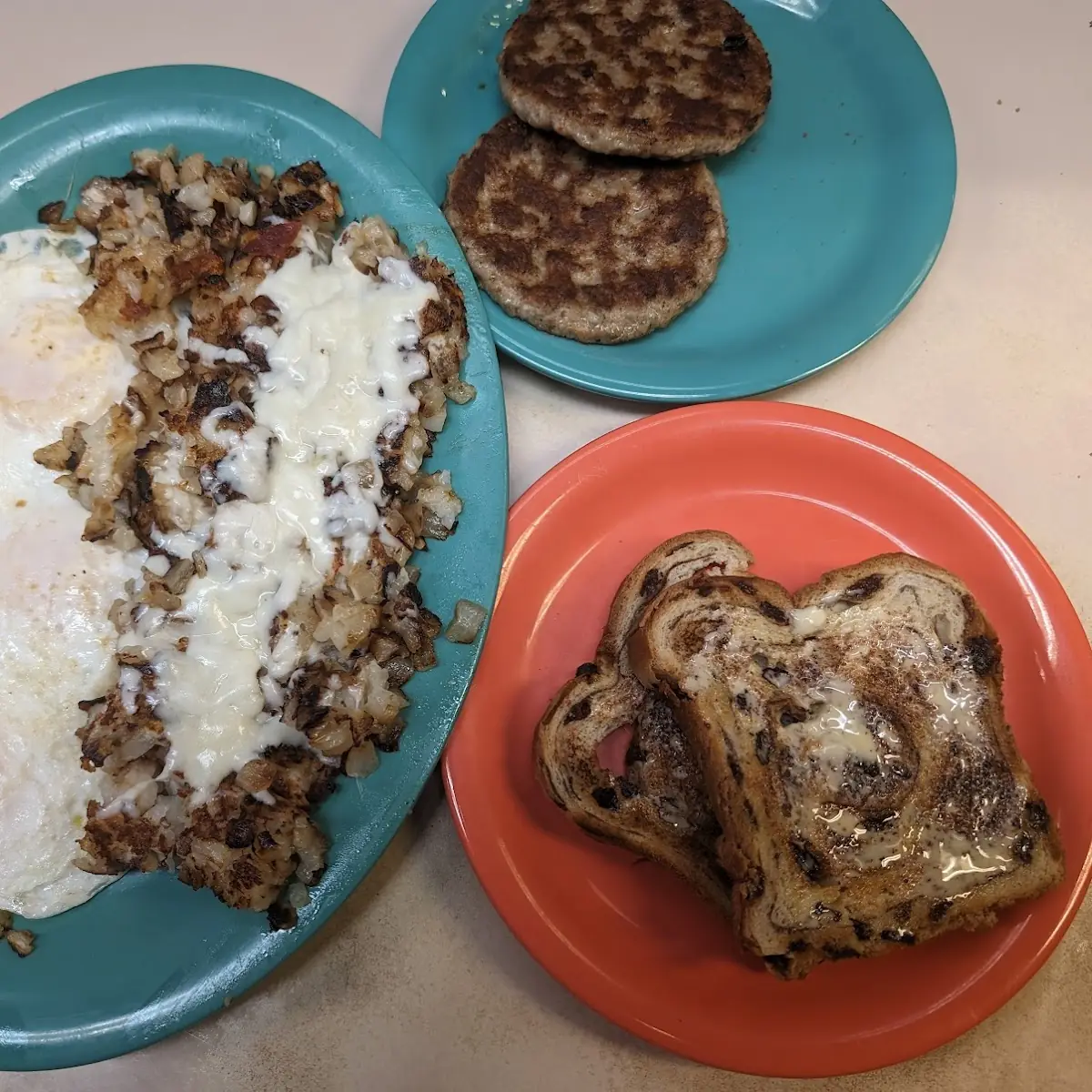 Three Eggs over Easy Hash Browns with Fried Onions and Mozzarella Cheese and Cinnamon Raisin Toast