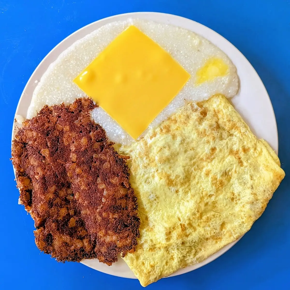 Bacon Ham and Cheese Omelet with Cheese Grits and Corned Beef Hash