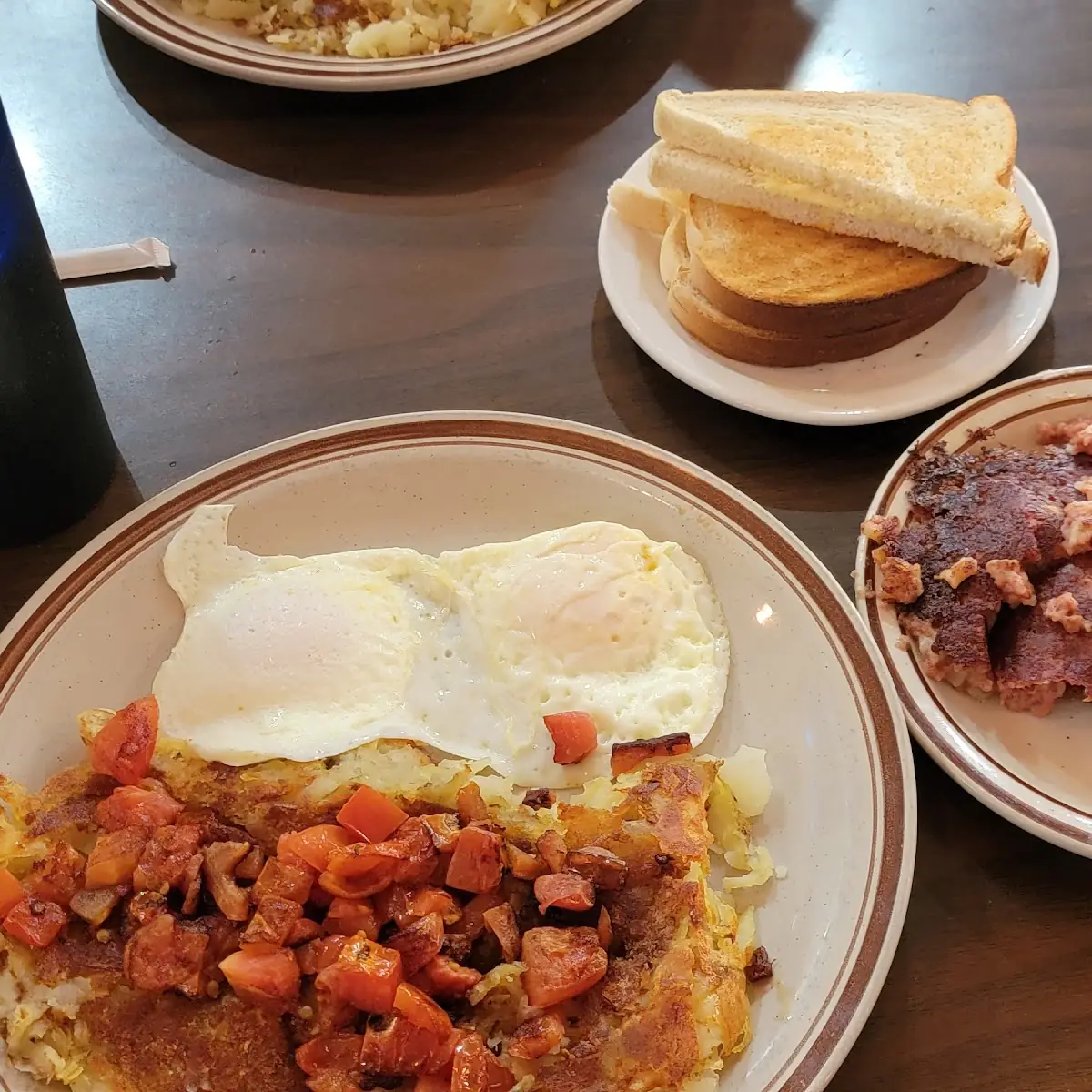 Corned Beef Hash 2 over Easy Eggs Crispy Hash Browns with Dice Tomatoes on Top White Toast