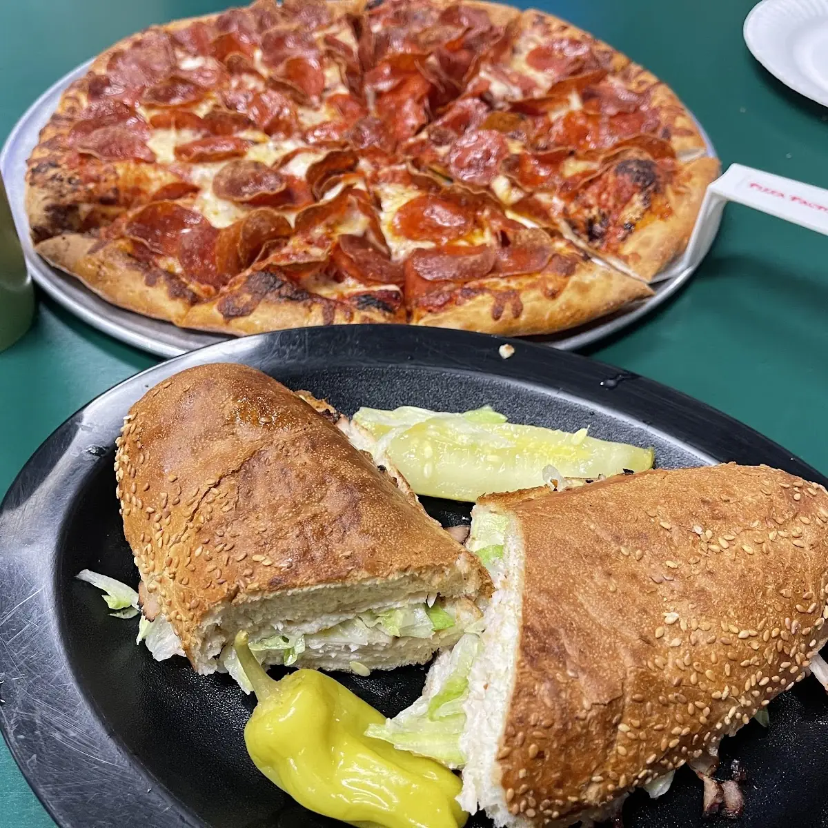 Turkey Sandwitch with Pepperoni Pizza in the Background