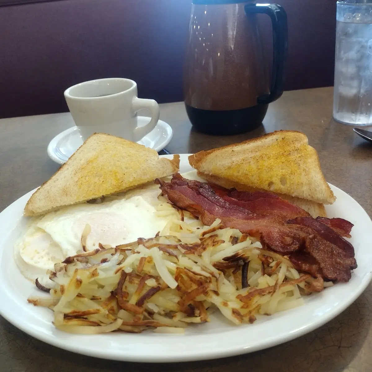 Three Eggs over Medium Hash Browns and Bacon and Toast