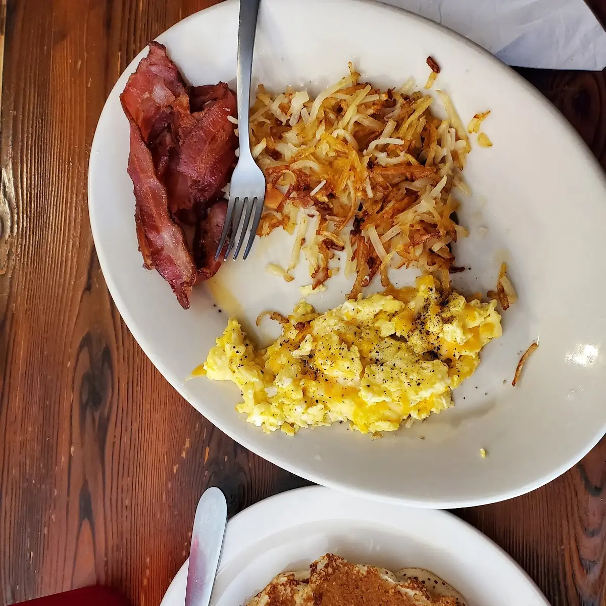 Custom Breakfast Dish Requested Scrambled Eggs with Cheddar Cheese Hash Browns Bacon and One Pancake