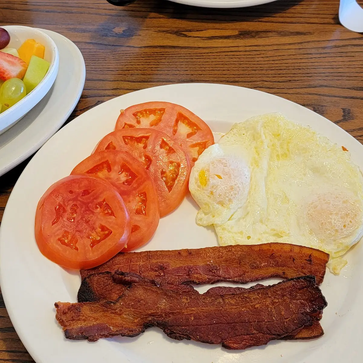 Eggs over Easy Bacon Sliced Tomatoes and Fresh Fruit