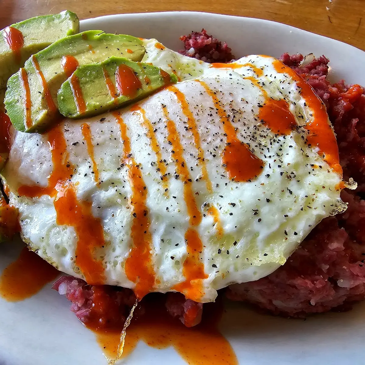 Corned Beef Hash with Eggs Avocado and Hot Sauce