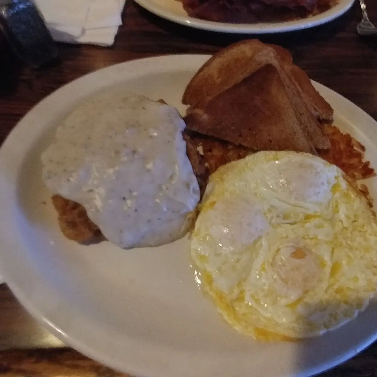 Chicken Fried Steak Smothered with Gravy Three Eggs over Easy Home Fries and Whole Wheat Toast