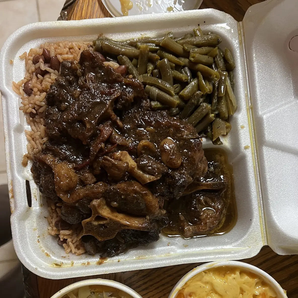 Oxtails over Rice and Beans String Beans Cabbage and Mac N Cheese