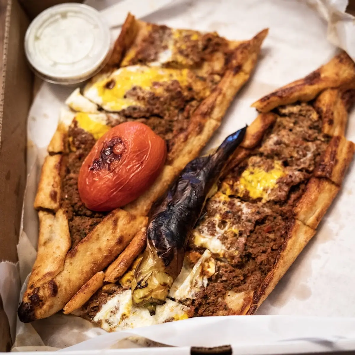 Pide Ephesus with Egg Thin Crust Pide Ephesus Topped with an Egg Grilled Hot Peppers & Tomatoes